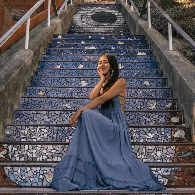 A woman poses sitting on the 16th Avenue tiled stairs 在 Sunset neighborhood of San Francisco.